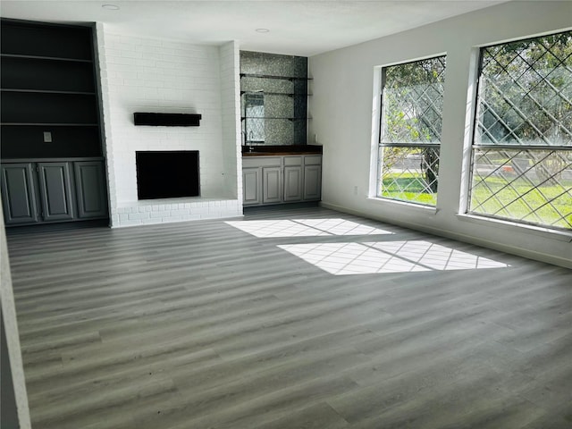 unfurnished living room with light hardwood / wood-style flooring and a brick fireplace