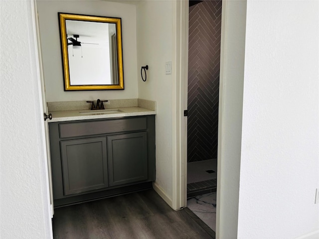 bathroom featuring vanity, a tile shower, and wood-type flooring