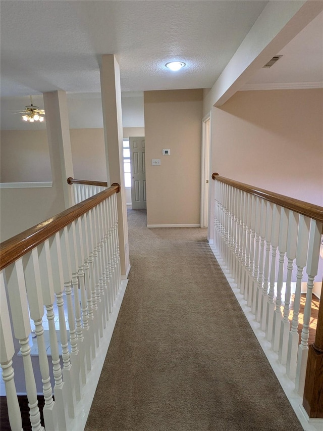 corridor featuring carpet flooring, a textured ceiling, and ornamental molding