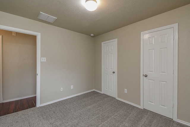 unfurnished bedroom with a textured ceiling and dark carpet