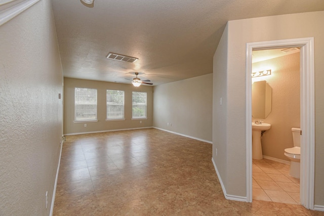 unfurnished room with ceiling fan, sink, light tile patterned floors, and a textured ceiling