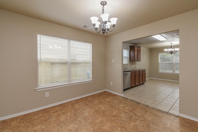 kitchen with dishwasher, light tile patterned floors, decorative light fixtures, and a notable chandelier