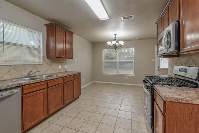 kitchen with sink, stainless steel appliances, a chandelier, decorative backsplash, and light tile patterned floors