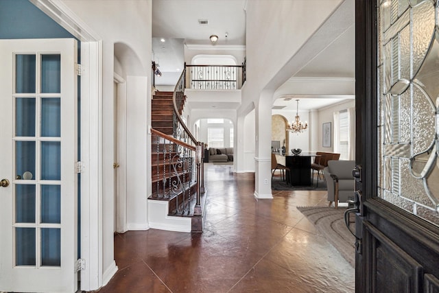 foyer entrance with crown molding and an inviting chandelier