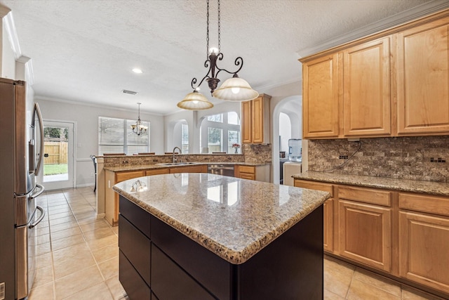 kitchen with decorative light fixtures, a kitchen island, appliances with stainless steel finishes, and tasteful backsplash