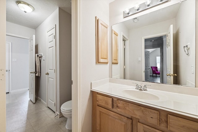 bathroom featuring tile patterned flooring, vanity, a textured ceiling, and toilet