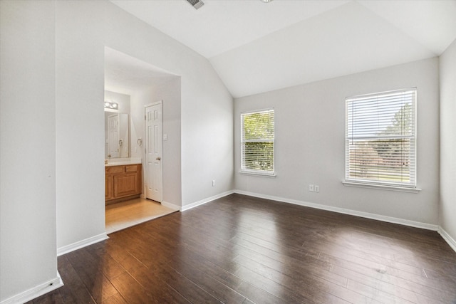 unfurnished bedroom with dark hardwood / wood-style flooring, lofted ceiling, and connected bathroom