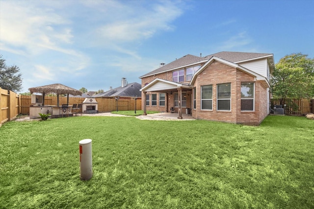 back of property featuring a fireplace, a gazebo, a patio, and a yard