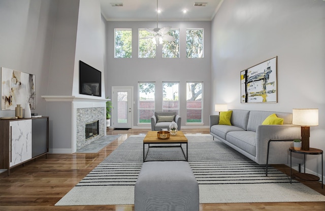 living room featuring hardwood / wood-style floors, a healthy amount of sunlight, crown molding, and a tiled fireplace