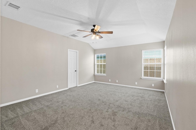 carpeted spare room with a textured ceiling, ceiling fan, plenty of natural light, and vaulted ceiling