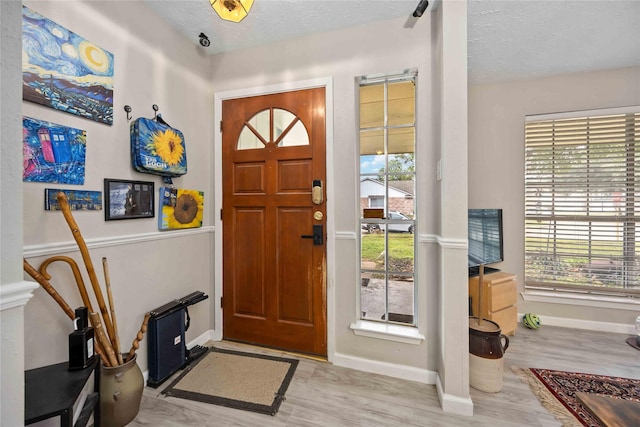 entryway featuring light wood-type flooring, a textured ceiling, and a wealth of natural light