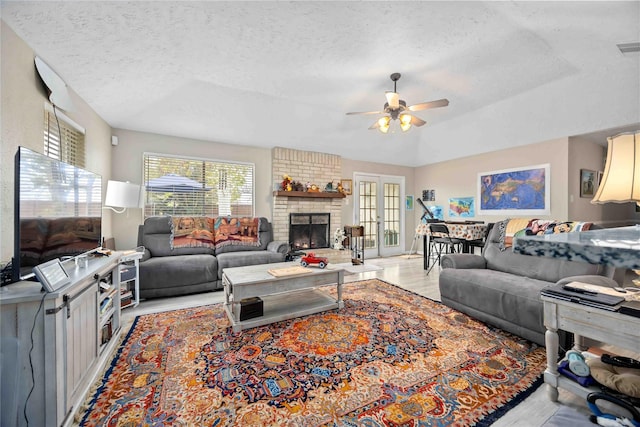 living room featuring a fireplace, a textured ceiling, and ceiling fan