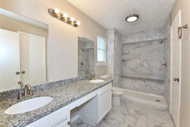 bathroom featuring vanity, toilet, tiled shower, and a textured ceiling