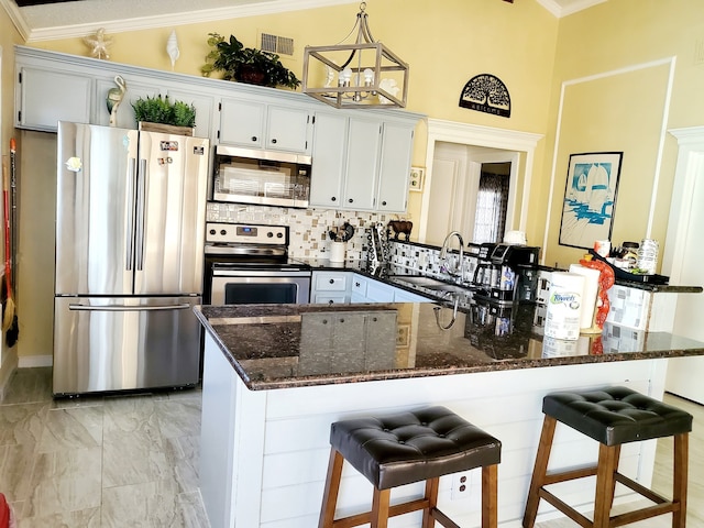 kitchen with appliances with stainless steel finishes, a breakfast bar, sink, white cabinetry, and lofted ceiling