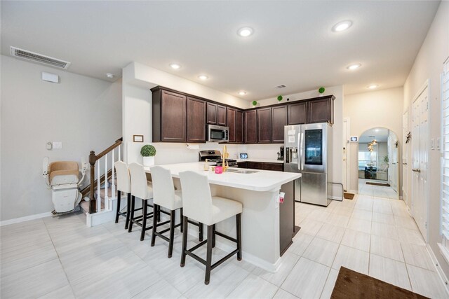 kitchen featuring dark brown cabinetry, sink, a kitchen breakfast bar, kitchen peninsula, and appliances with stainless steel finishes