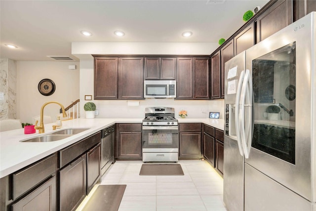 kitchen featuring appliances with stainless steel finishes, dark brown cabinetry, light tile patterned floors, and sink