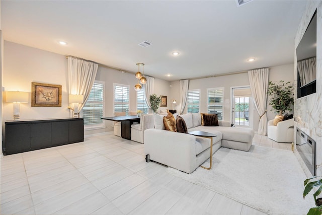 living room featuring a fireplace, light tile patterned floors, and a wealth of natural light