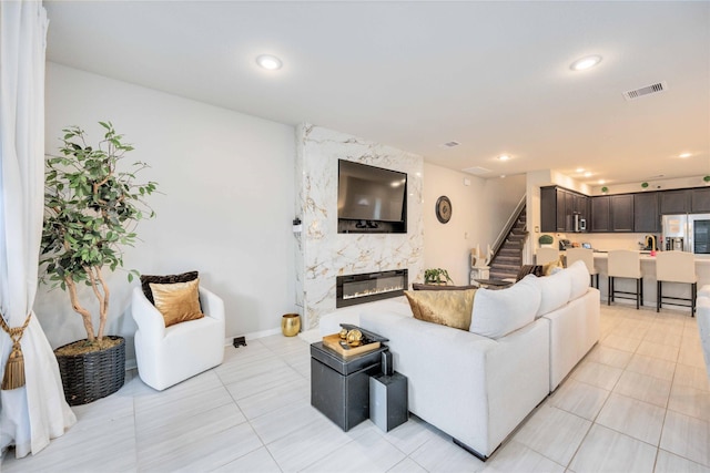 living room with light tile patterned flooring and a high end fireplace