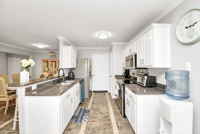 kitchen featuring kitchen peninsula, stainless steel appliances, sink, white cabinets, and a breakfast bar area