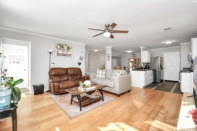 living room featuring crown molding, sink, ceiling fan, and light wood-type flooring