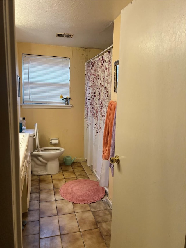 bathroom featuring toilet, a textured ceiling, vanity, and tile patterned floors