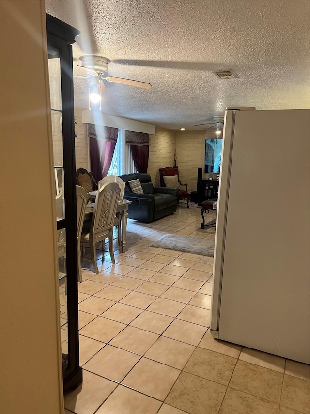 living area with visible vents, ceiling fan, a textured ceiling, and light tile patterned floors