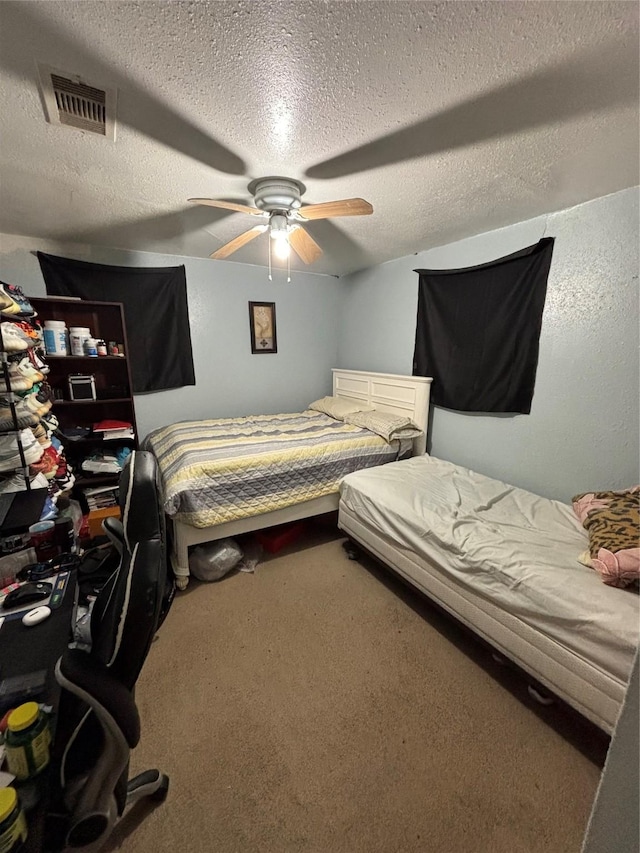 carpeted bedroom featuring a textured ceiling, visible vents, and a ceiling fan