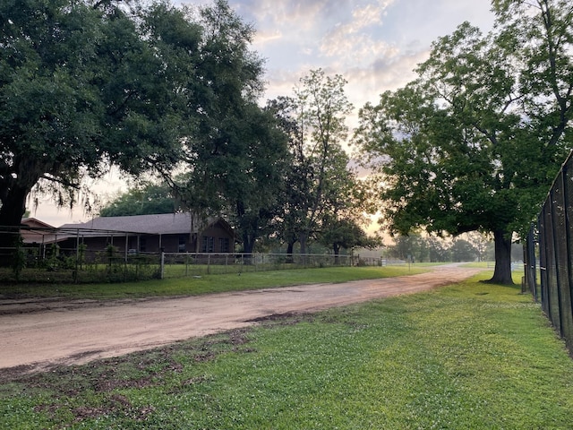 yard at dusk featuring fence and driveway