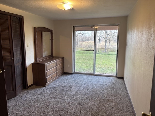 unfurnished bedroom with access to outside, carpet, baseboards, and a textured ceiling