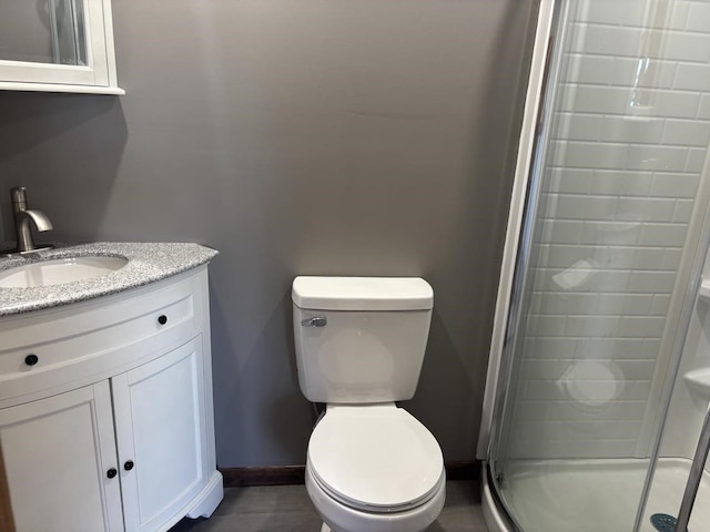 bathroom featuring a shower stall, toilet, vanity, and baseboards