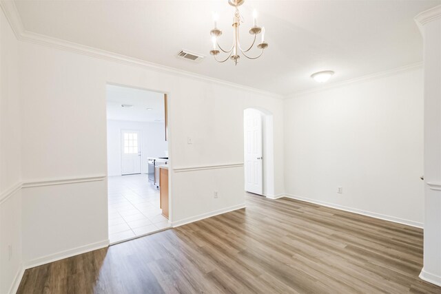 empty room with light wood-type flooring, an inviting chandelier, and ornamental molding