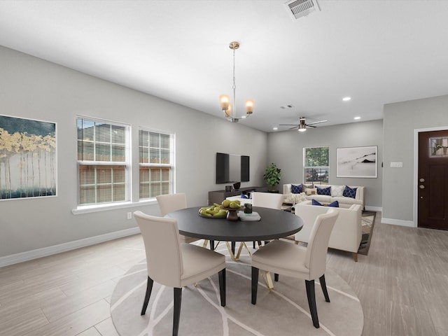 dining space with light hardwood / wood-style floors and ceiling fan with notable chandelier