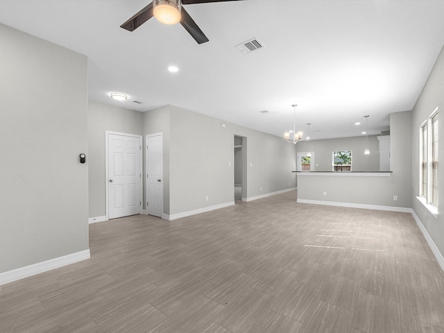 unfurnished living room with ceiling fan with notable chandelier