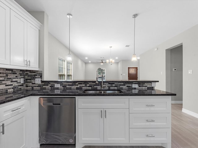 kitchen with stainless steel dishwasher, white cabinets, sink, and dark stone counters