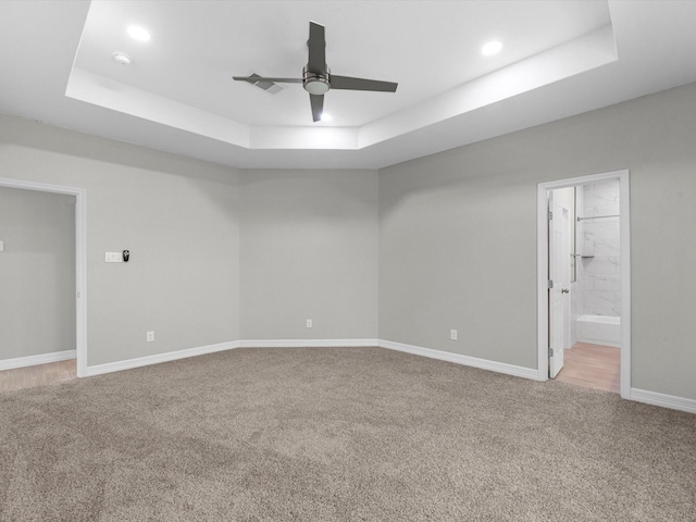 empty room with carpet, ceiling fan, and a raised ceiling