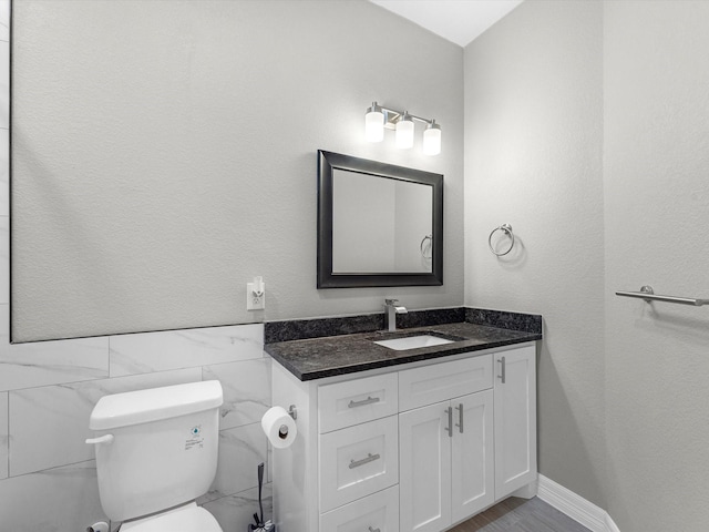 bathroom featuring vanity, tile walls, and toilet