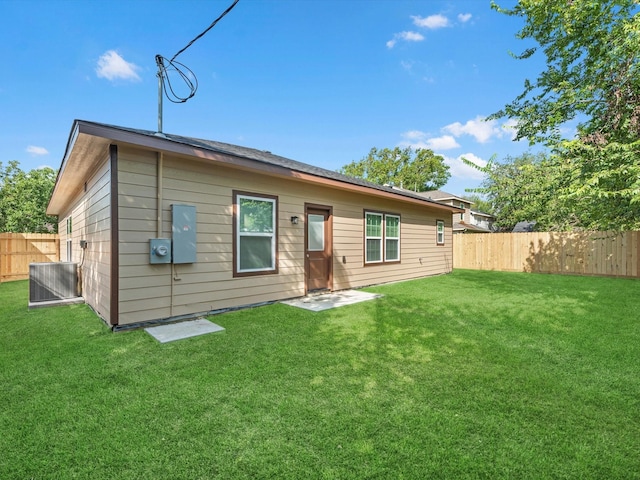 back of house with cooling unit and a lawn