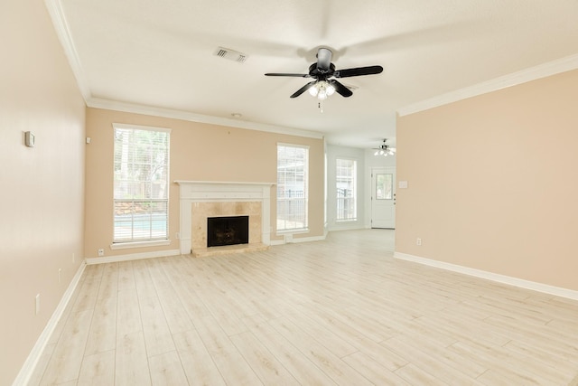 unfurnished living room featuring a tiled fireplace, ceiling fan, ornamental molding, and light wood-type flooring