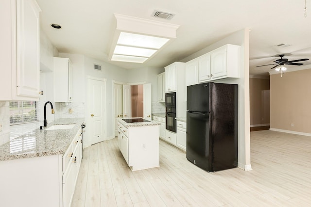 kitchen featuring black appliances, a kitchen island, white cabinetry, and sink