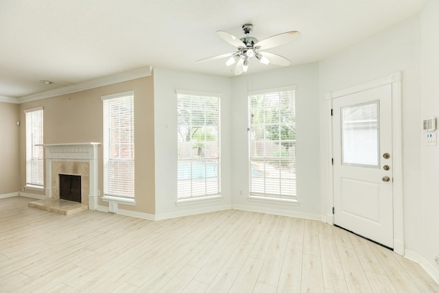 unfurnished living room with a tiled fireplace, plenty of natural light, and light wood-type flooring