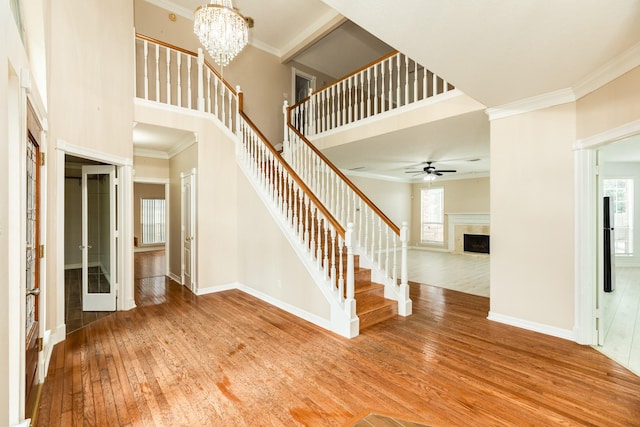 entrance foyer featuring hardwood / wood-style floors, ceiling fan with notable chandelier, a high ceiling, and ornamental molding