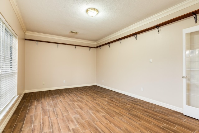 empty room with hardwood / wood-style flooring, a healthy amount of sunlight, ornamental molding, and a textured ceiling