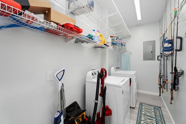 washroom featuring electric panel, washer and dryer, and light wood-type flooring