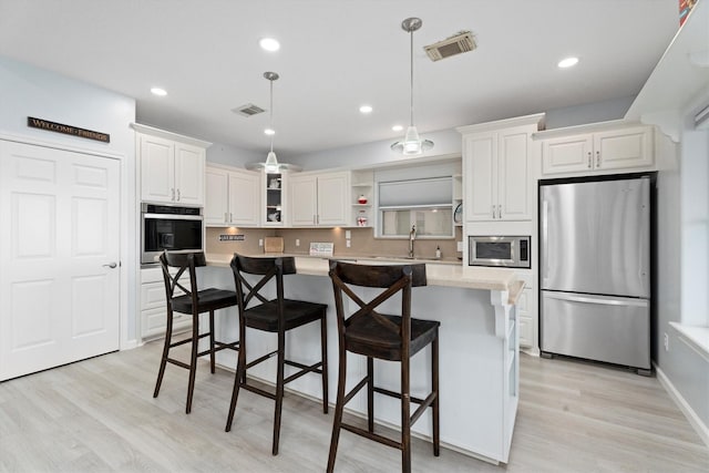 kitchen featuring white cabinets, a kitchen island, hanging light fixtures, and appliances with stainless steel finishes