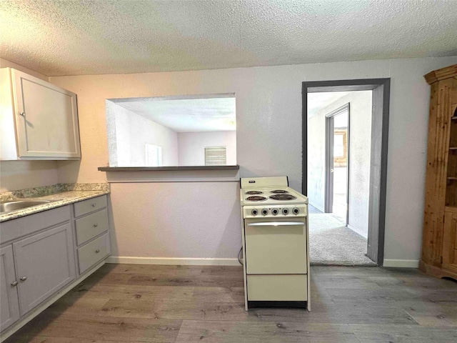 kitchen with light wood-type flooring, a textured ceiling, white range, sink, and white cabinetry