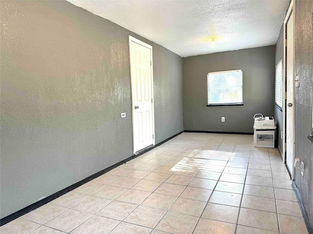 spare room featuring a textured ceiling and light tile patterned flooring