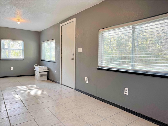 unfurnished room with plenty of natural light, light tile patterned floors, and a textured ceiling