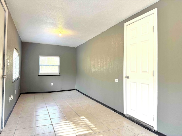 tiled empty room featuring a textured ceiling