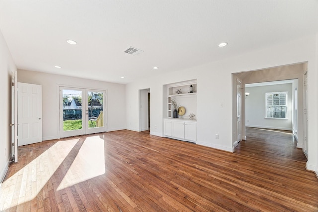 unfurnished living room with built in shelves, french doors, and hardwood / wood-style floors