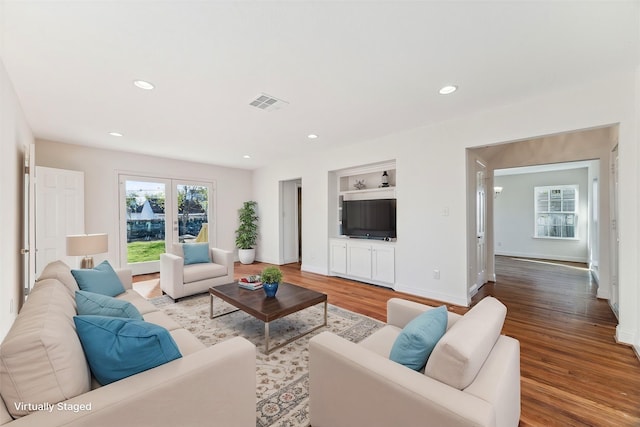 living room featuring built in shelves, wood-type flooring, and french doors